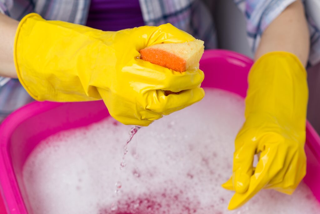 Basin of soapy water with scrubbing sponge to remove stains from carpet